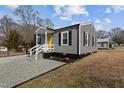 Side view of a cozy home with gray siding, black trim and a bright yellow door at 704 Dothan Ave, Burlington, NC 27217