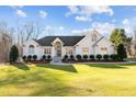 Charming white brick home with a manicured lawn, mature trees and an inviting entrance with white pillars at 1002 Pleasant Dr, Mebane, NC 27302