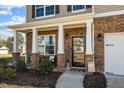 Inviting front porch with stone accents, decorative columns, and a cozy seating area at 1020 Broadlands Way, Graham, NC 27253