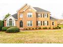 Charming two-story brick home features a well-manicured lawn and lush greenery at 10620 Staghound Trl, Zebulon, NC 27597