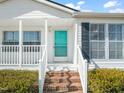 Inviting front porch with brick steps, white railing, and a charming turquoise door at 1304 Nc 96 Hwy S, Zebulon, NC 27597