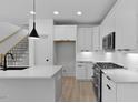 Open kitchen with island, white cabinets, and stainless steel appliances at 140 E End Ave # 2, Durham, NC 27703