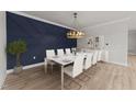 Modern dining room featuring white furniture, stylish chandelier, and a striking blue accent wall at 1400 Gathering Park Cir # 202, Cary, NC 27519