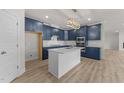 Modern kitchen with white island, blue cabinets, stainless steel appliances, and hardwood floors at 1400 Gathering Park Cir # 204, Cary, NC 27519