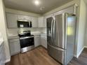 The modern kitchen features gray cabinets, stainless steel appliances, granite countertops, and luxury vinyl flooring at 181 Pate Landing Dr, Selma, NC 27576