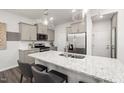 Bright kitchen featuring white backsplash, stainless steel appliances, an island, gray cabinets, and stylish pendant lighting at 3410 Pelican Ln, Durham, NC 27703