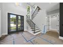 Bright foyer with a staircase, modern lighting, and black framed glass paneled front door at 7412 Wexford Woods Ln, Wake Forest, NC 27587