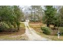 Home nestled among mature trees with a long gravel driveway and a well-maintained front yard at 2010 Twin Acres Rd, Clayton, NC 27520