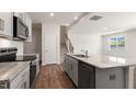 Open kitchen featuring gray cabinets, granite countertops, a kitchen island, and stainless steel appliances at 266 Hanging Elm Ln, Fuquay Varina, NC 27526