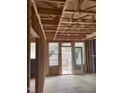 Unfinished living room showcasing the bare framework, windows, and door that leads to the backyard at 4073 Elk Creek Ln, Raleigh, NC 27612