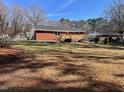 Wide shot of the property's rear, showcasing a spacious backyard with a wooden deck and mature trees at 613 Sexton Ave, Zebulon, NC 27597
