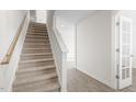 Carpeted staircase with white trim and wood railing, adjacent to a door with glass panes at 864 Forth Ct # 150, Gibsonville, NC 27249