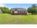 Spacious backyard with green grass, featuring a brick house with a cozy back porch at 105 Pinecrest Dr, Angier, NC 27501