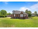 Large backyard with a well-manicured lawn, brick house, and mature trees at 105 Pinecrest Dr, Angier, NC 27501