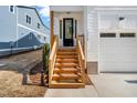 The wooden porch stairs lead to a stylish front door with black frame, complemented by modern lighting at 1215 Chaney Rd, Raleigh, NC 27606
