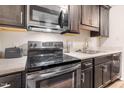 Close up of stainless steel oven, range, microwave, sink, cabinets, and countertops in the kitchen at 1287 Schaub Dr # J, Raleigh, NC 27606
