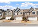 Inviting townhomes showcasing attached garages, stone details, and well-manicured landscaping on a sunny day at 468 Talons Rest Way, Cary, NC 27513