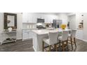 Bright kitchen features white cabinets, stainless appliances, and a large center island with seating at 1305 White Verona Way, Knightdale, NC 27545