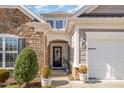 Close-up shot of a home's front entrance, showcasing the stone facade and inviting front door with decorative wreath at 221 Elverson Pl, Cary, NC 27519