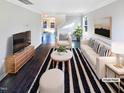 Bright living room with modern decor, white sofa and chairs, striped rug, and dark wood floors at 6025 Herston Rd, Raleigh, NC 27610
