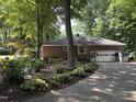 View of the brick home with an attached garage, surrounded by meticulously landscaped gardens and lush greenery at 8701 Oneal Rd, Raleigh, NC 27613