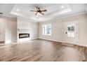Bright living room with modern fireplace, tray ceiling, ceiling fan, and beautiful laminate flooring at 9230 Bear Run Ln, Middlesex, NC 27557
