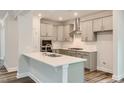 Modern kitchen featuring sleek gray cabinetry, stainless steel appliances, and a quartz-topped island with a sink at 187 E Fountainhead Ln, Garner, NC 27529