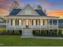 Inviting two-story home with a spacious front porch, manicured landscaping, and a vibrant sunset backdrop at 304 Ashley Woods Ct, Clayton, NC 27527