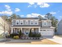 Charming two-story home features a covered front porch, manicured lawn, and attached two-car garage at 401 River Falls Dr, Apex, NC 27539