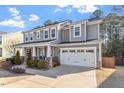 Charming two-story home features a covered front porch, manicured lawn, and attached two-car garage at 401 River Falls Dr, Apex, NC 27539