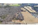 Aerial view of a large property with a home nestled among trees and open fields in the countryside at 4639 Reid Rd, Elon, NC 27244