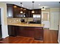 Modern kitchen with rich dark wood cabinets, granite countertops, stainless steel appliances, and hardwood floors at 610 Westbrook Dr, Burlington, NC 27215