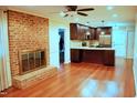 Open concept living room featuring a brick fireplace, hardwood floors, and an adjacent kitchen area at 610 Westbrook Dr, Burlington, NC 27215