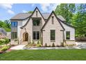 Beautiful home exterior with a decorative brick facade, gabled roof, arched entrance, and professionally landscaped yard at 7621 Wingfoot Dr, Raleigh, NC 27615