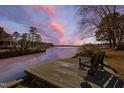 Wooden dock features a chair overlooking the serene lake and colorful sky at 79 Cove Lndg, Sanford, NC 27332