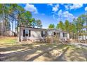 Attractive one-story home with a cozy porch, set on a lot with scattered trees beneath a bright, cloudy sky at 112 Mckoy Town Rd, Cameron, NC 28326