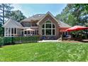 Expansive backyard featuring a brick house with outdoor seating areas and lush lawn at 12085 Morehead, Chapel Hill, NC 27517