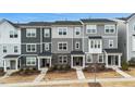A daytime shot of the exterior of gray townhouses with stone facade accents, well-maintained landscaping, and individual entrances at 1430 Rosepine Dr, Cary, NC 27519