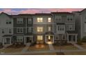 Modern townhomes with gray siding, stone accents, covered entries, and landscaped front yards offer curb appeal at dusk at 1430 Rosepine Dr, Cary, NC 27519