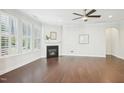 A spacious living room with a cozy fireplace, ceiling fan, large windows, and elegant dark wood flooring at 1951 Mostyn Ln, Apex, NC 27502