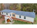 An aerial view shows the house has a new roof, a yard and a ramp for accessibility, surrounded by lush trees at 6508 Treetop Ct, Snow Camp, NC 27349
