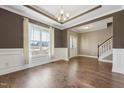 Elegant living room with hardwood floors, crown molding, wainscoting, a large window and modern chandelier at 109 Hammermill Dr, Fuquay Varina, NC 27526