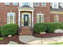 Inviting front entrance with a black front door, sidelights, and manicured shrubs at 1154 Smith Creek Way, Wake Forest, NC 27587