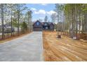 Stately two-story home with blue siding, stone accents, a long driveway, and picturesque natural surroundings at 140 Pilot Ridge Rd, Zebulon, NC 27597