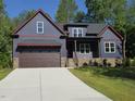 Two-story home with a dark-blue exterior, covered porch, and an attached two-car garage at 140 Pilot Ridge Rd, Zebulon, NC 27597