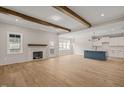 Open-concept living room features wood floors, fireplace, exposed beams and modern kitchen with island at 140 Pilot Ridge Rd, Zebulon, NC 27597