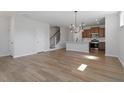 Open-concept living room showcasing the hardwood floors, modern light fixture, and kitchen at 203 Frosted Iris Lane St # 181, Garner, NC 27529