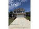 Two-story home featuring a spacious garage, gray siding, and a well-manicured front lawn on a sunny day at 542 Winding Crk Dr, Lillington, NC 27546