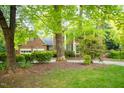 A view of the front of a brick home with large trees in the front yard at 826 Warwick Ct, Burlington, NC 27215