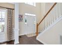 Bright foyer with a wooden staircase, coat closet, and large window with natural light at 104 Spooner Ct, Holly Springs, NC 27540